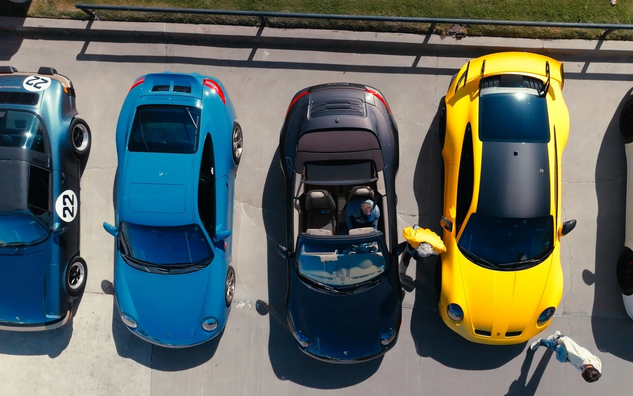 Four cars parked nose to tail, seen from above, a yellow 911 on the end